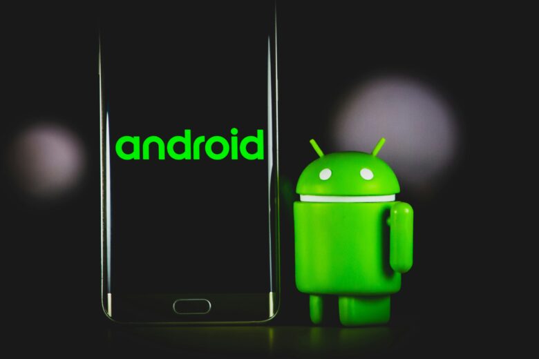 Mascota oficial de Android junto a un smartphone con el logo de Android en pantalla