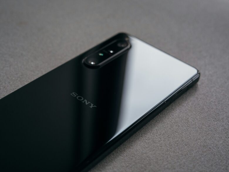 Parte trasera de un smartphone Sony Xperia negro brillante con triple cámara sobre superficie gris